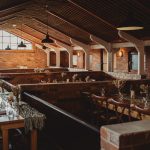 Rustic banquet hall with wooden tables and brick walls.