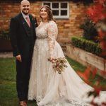 Couple in wedding attire smiling outdoors.