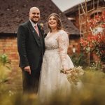 Couple celebrating wedding outdoors near brick building.