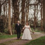 Bride and groom walking in forest path