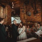 Wedding ceremony in rustic brick venue, couple exchanging vows.