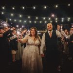 Bride and groom holding sparklers at night celebration.