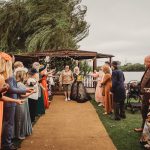 Wedding guests celebrating newlyweds on garden pathway.