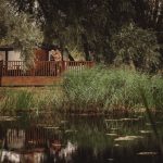 Lakeside yurt with couple on deck, lush greenery