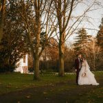 Bride and groom in autumnal garden setting.