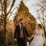 Bride and groom walking in autumn forest.