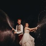 Couple joyfully spraying champagne together