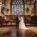 Bride and groom in a church with stained glass.