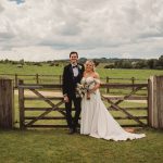 Bride and groom standing by country gate