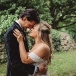 Bride and groom embracing in garden setting.