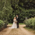 Bride and groom standing on garden path.