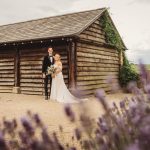 Couple posing by rustic barn with lavender foreground.