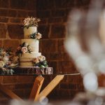 Rustic wedding cake with floral decorations on table.