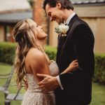 Couple embracing outdoors in wedding attire.