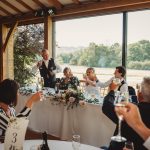 Wedding toast at reception with guests raising glasses.