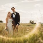 Bride and groom in a field, sunny day.