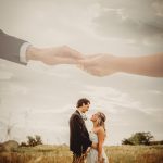 Romantic couple holding hands in sunny field.