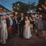 Newlyweds walking through guests holding sparklers.