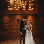 Bride and groom in front of illuminated LOVE sign