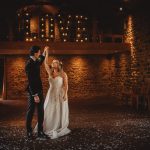 Bride and groom dancing under love sign.