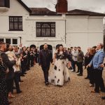 Bride and groom exit wedding ceremony, guests cheering.