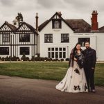 Couple in wedding attire outside manor house