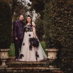 Couple in formal attire standing in a garden.