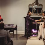 Gothic wedding ceremony, couple handfasting by fireplace.