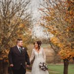 Bride and groom walking in autumn park.