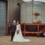 Bride and groom standing by industrial container