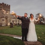 Wedding couple with sparklers outside church.