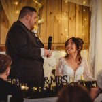 Groom gives wedding speech, bride smiles