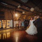 Bride and groom dancing under fairy lights at wedding.