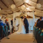 Bride and groom kiss at indoor wedding ceremony.