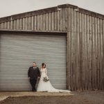 Bride and groom outside rustic barn door.