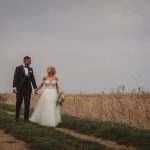 Bride and groom walking in field.