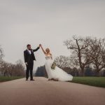 Bride and groom dancing on tree-lined path.