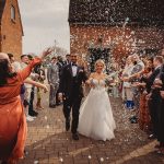 Bride and groom walking through confetti shower.