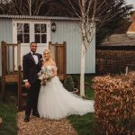 Bride and groom outdoors by rustic cabin.