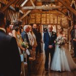 Bride walking down aisle in rustic venue.