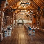 Rustic barn wedding venue with wooden beams and chairs.