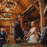 Couple exchanging vows in rustic barn wedding.