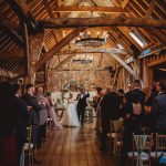 Bride and groom walking down rustic barn aisle.