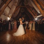 Bride and groom's first dance, surrounded by guests.