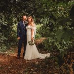 Bride and groom in forest path, wedding day.