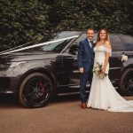 Bride and groom beside decorated wedding car.