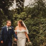 Bride and groom holding hands outdoors.