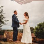 Couple holding hands on their wedding day outdoors.