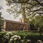 Historic church surrounded by lush greenery and trees.