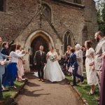 Bride and groom leaving church amid confetti celebration.